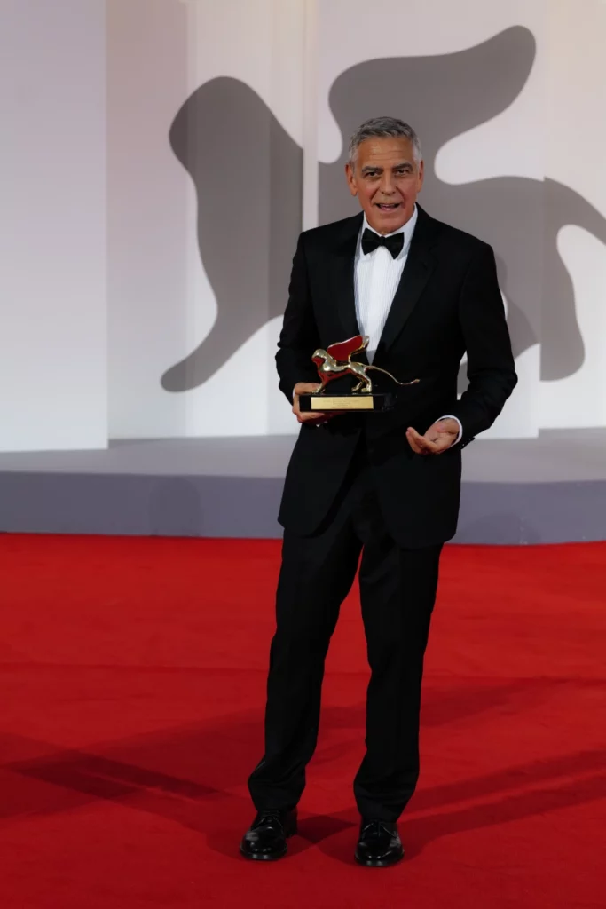 George Clooney gesturing while holding the Golden Lion award, Venice Film Festival 2026 – Ph. Barbara Pigazzi, Studio Animica